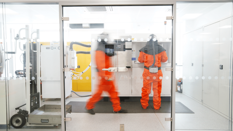 Two manufacturing engineers wearing orange suits